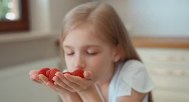 Dziewczyna portret zbliżenie wąchania jagody. Dziecko trzyma garść malin i patrząc na kamery i uśmiechając się — Wideo stockowe
