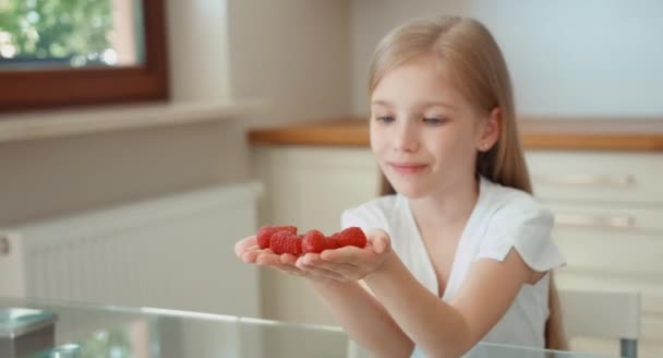 Child holds a handful of raspberries and gives its audience. Looking at camera and smiling — Stock Video