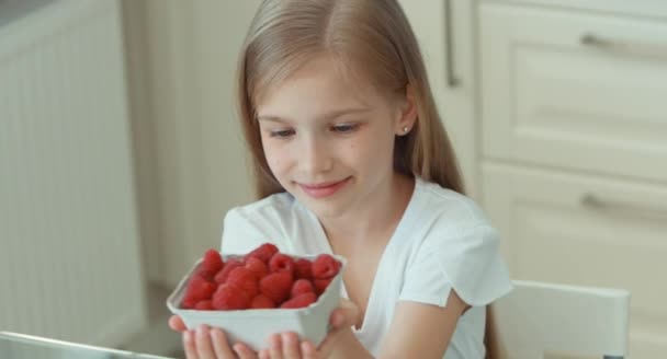 Girl sniffing raspberries and gives the viewer a basket — Stock Video