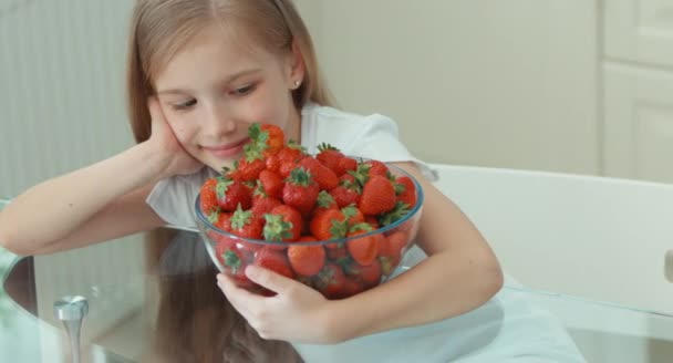 Mädchen umarmt großen Teller mit Erdbeeren und lacht in die Kamera — Stockvideo