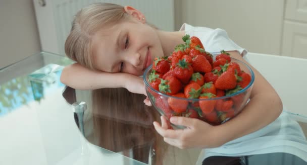 Girl hugging big plate of strawberries and looking at camera — Stock Video