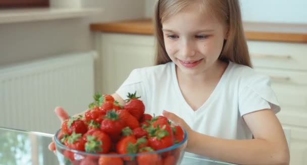 Retrato chica comiendo fresas grandes y mirando a la cámara — Vídeo de stock