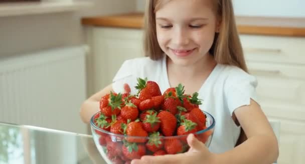 Retrato rindo menina com grande prato de morangos e olhando para a câmera — Vídeo de Stock