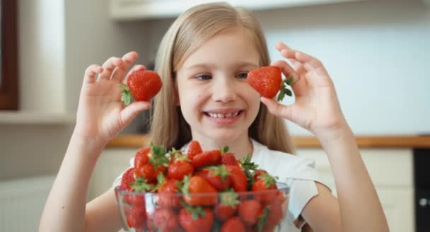 Nahaufnahme Porträt eines Mädchens mit Erdbeeraugen. Kind lacht und blickt in Kamera — Stockvideo