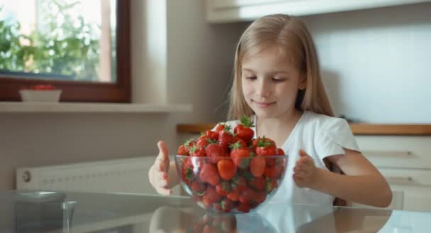 Chica admirando un gran plato de fresas y mirando a la cámara — Vídeo de stock