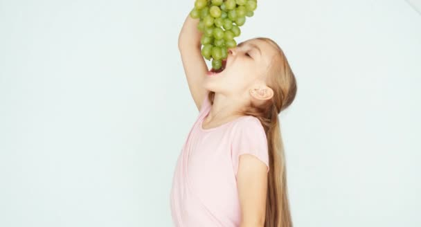 女孩抱着葡萄和吃它。大拇指。还行 — 图库视频影像
