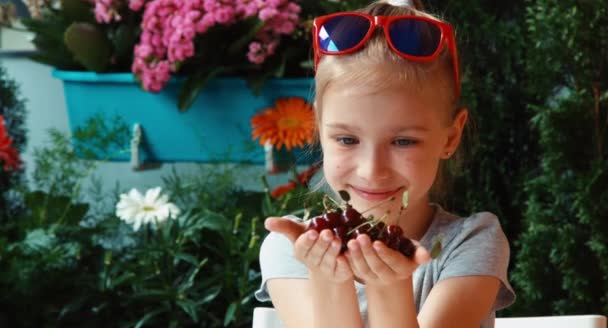 Mädchen hält eine Handvoll Kirschen und bewundert Beeren und blickt in die Kamera — Stockvideo