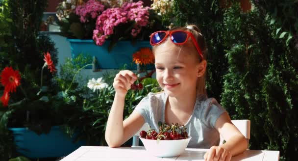 Chica sosteniendo una cereza. Niño comiendo bayas y los admira — Vídeo de stock
