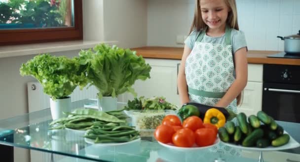 Young chef with vegetables near kitchen table. Girl promoting healthy food — Stock Video