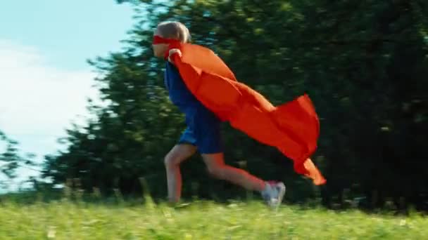 Щасливий супергерой 7-8 років біжить на блакитне небо — стокове відео