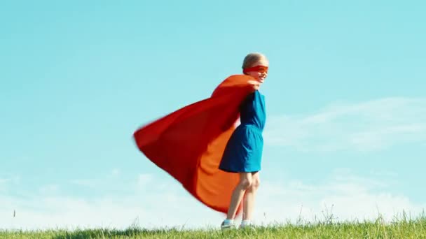 Glad superhjälte flicka barn 7-8 år gammal spinning mot den blå himlen — Stockvideo