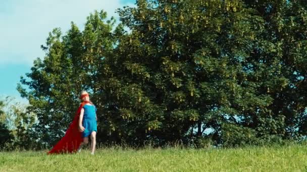 Glücklich Superheldenmädchen Kind 7-8 Jahre alt läuft gegen den blauen Himmel — Stockvideo