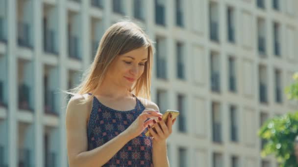 Jovem adulto usando smartphone ao ar livre e sorrindo para a câmera — Vídeo de Stock