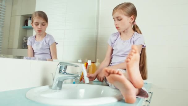 Дівчина використовує зубну щітку і зубну пасту, сидячи біля дзеркала — стокове відео