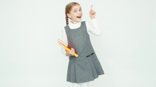 Retrato linda colegiala 7-8 años sosteniendo libros sobre fondo blanco. Dedo arriba. Idea Ok — Vídeos de Stock