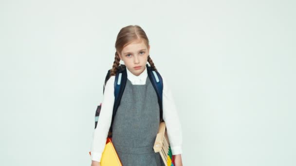 Portrét smutné školačka dítě 7-8 let s batoh drží abacus a knihy na bílém pozadí při pohledu na fotoaparát — Stock video