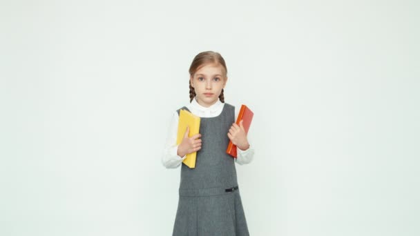 Colegiala 7-8 años sosteniendo libros y mirando a la cámara — Vídeos de Stock