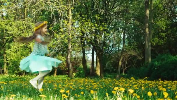 Bahar kraliçesi kız 7-8 yaş arası dandelions kafasına parkta iplik ve güneşe gülümseyen çelenk ile — Stok video