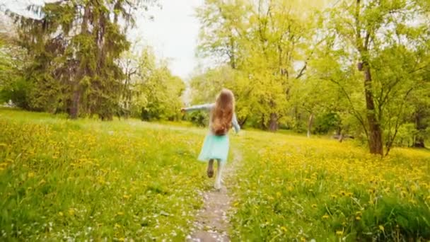 Chica feliz girando y corriendo en el parque en la primavera. Cámara lenta desde Sony A6300 — Vídeo de stock