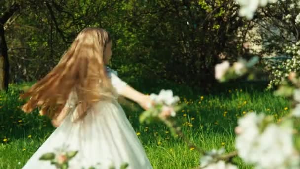 Портрет девочка ребенок 7-8 лет прядение в белом платье в парке рядом с цветущим деревом — стоковое видео