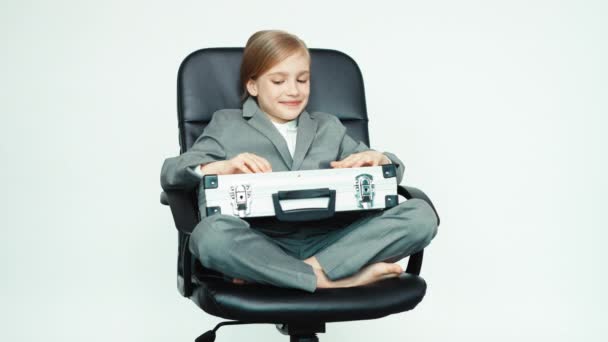 Biznes dziecko dziewczynka 7-8 lat z przypadku i telefon komórkowy na białym tle siedzi na krześle — Wideo stockowe