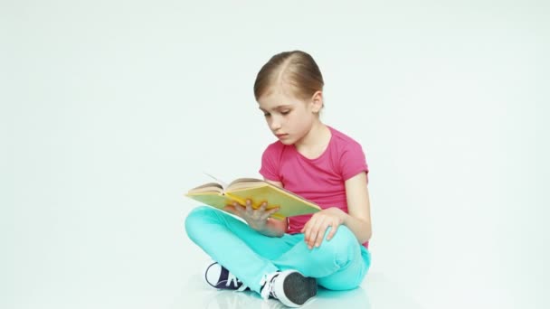 Cute girl 7-8 years reading book and laughing on white background. Slider in — Stockvideo