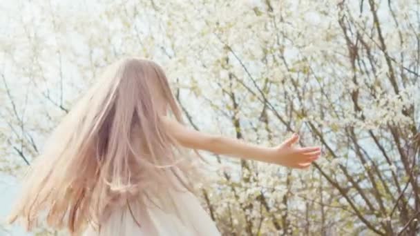 Girl 7 years old spinning in a dress on a background of blooming trees. Slow Motion Sony A6300 — Stockvideo