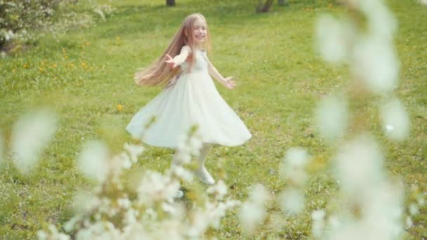 Блондинка кружится в белом платье на траве. Slow Motion Sony A6300 — стоковое видео