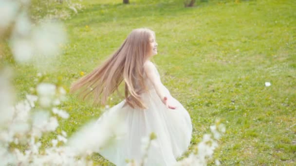 Lachende blonde Mädchen wirbeln in einem weißen Kleid auf dem Rasen. Zeitlupe sony a6300 — Stockvideo