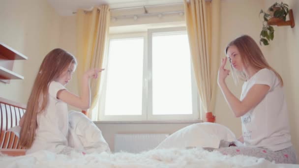 Fighting pillows on the bed. Mother and daughter in sunny bedroom. Among the fluff and feathers. Slowmotion — Stock video