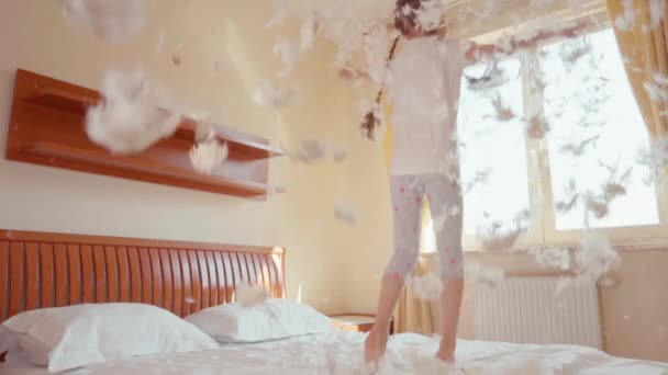 Fille heureuse sautant et tournant sur le lit. Parmi les peluches et les plumes. Mouvement lent — Video