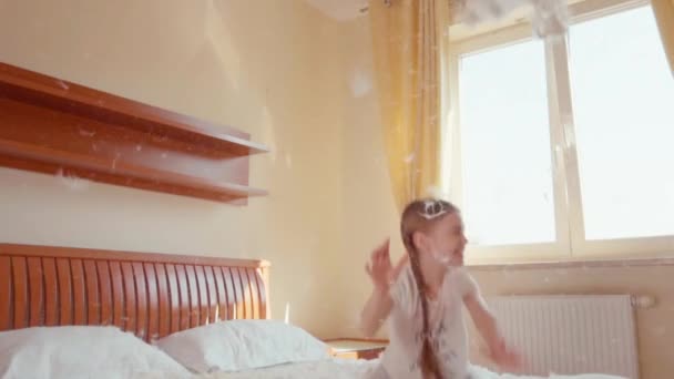 Happy girl jumping and spinning on the bed. Among the fluff and feathers 3. Slowmotion — Stock video
