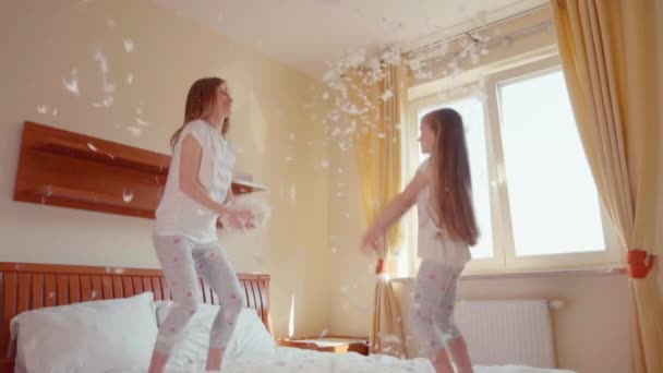 Happy daughter and mother jumping on the bed. Among the fluff and feathers. Slowmotion — Αρχείο Βίντεο