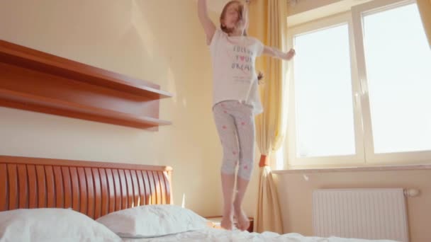 Glückliches Mädchen, das auf dem Bett springt und sich dreht. zwischen Flaum und Federn 2. Zeitlupe — Stockvideo