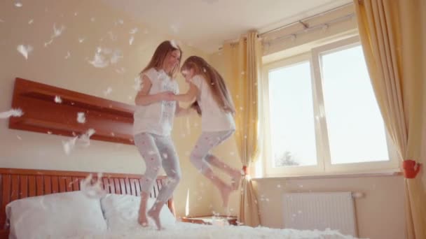 Gelukkige familie springen en draaien op het bed. Onder de pluisjes en veren. Slowmotion — Stockvideo