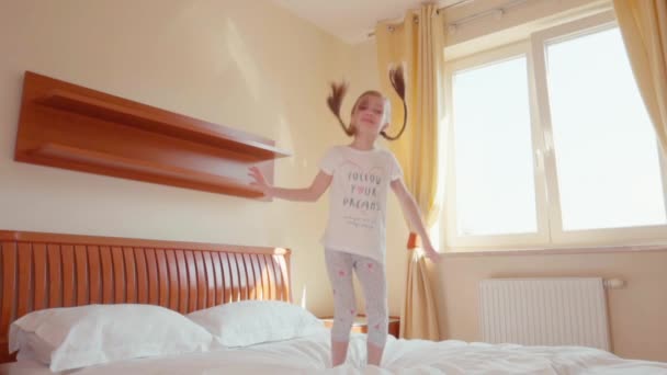 Menina feliz pulando e girando na cama. Movimento lento — Vídeo de Stock