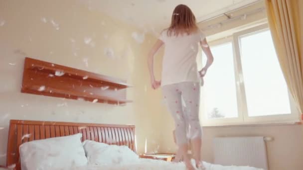 Filles mignonnes sautant et tournant sur le lit. Parmi les peluches et les plumes. Mouvement lent — Video