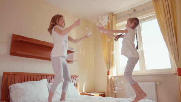 Happy family daughter and mother jumping and spinning on the bed. Among the fluff and feathers. Slowmotion — ストック動画