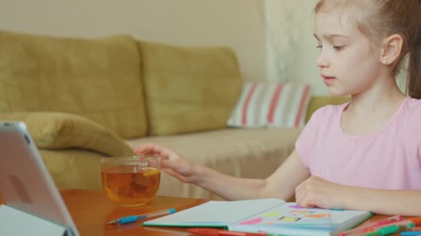 Schattig meisje 7 jaar oud zit in de tabel en het drinken van thee — Stockvideo