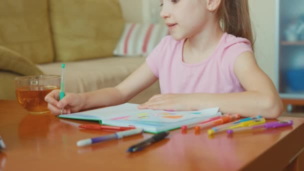 Portrait cute girl 7 years old sitting in the table and smiling at camera — Stock Video