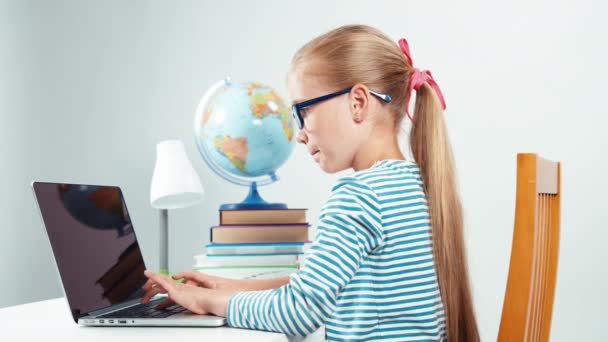 Portrait child 7-8 years old something typing on her laptop and laughing at camera — Αρχείο Βίντεο