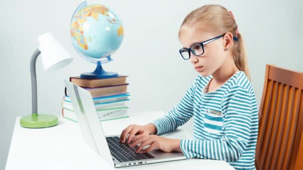 Retrato niño 7-8 años algo escribiendo en su computadora portátil y sonriendo a la cámara — Vídeo de stock