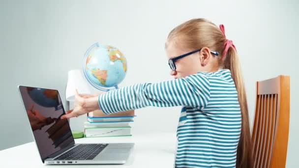 Schoolgirl using her laptop. Child stretching her hands and slowly typing on computer — ストック動画