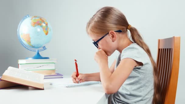 Portrait girl child student with a sad face sitting in the table. Isolated on white — Stock video