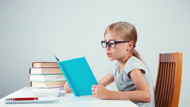 Lykkelig skolepike på 7-8 år som leser sin bok og leser med smil – stockvideo