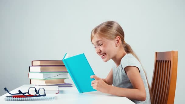 Happy schoolgirl 7-8 years old holding her book and reading with smile — Stock video