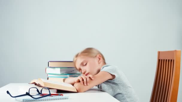 Tired schoolgirl 7-8 years does not want read a book. Student wants to sleep — Stockvideo