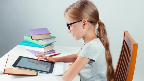 Девочка-студентка 7-8 лет с планшетным компьютером на столе. Вид сверху — стоковое видео
