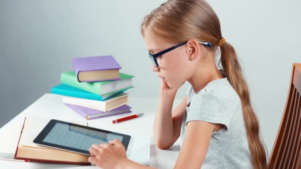 Primer plano retrato perfil estudiante niña niño 7-8 años de edad utilizando tableta PC en su escritorio y mirando a la cámara con sonrisa. Vista superior — Vídeos de Stock