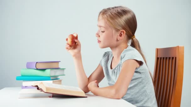 Portrait student girl child 7-8 years reading book and eating fruit. Isolated — Αρχείο Βίντεο